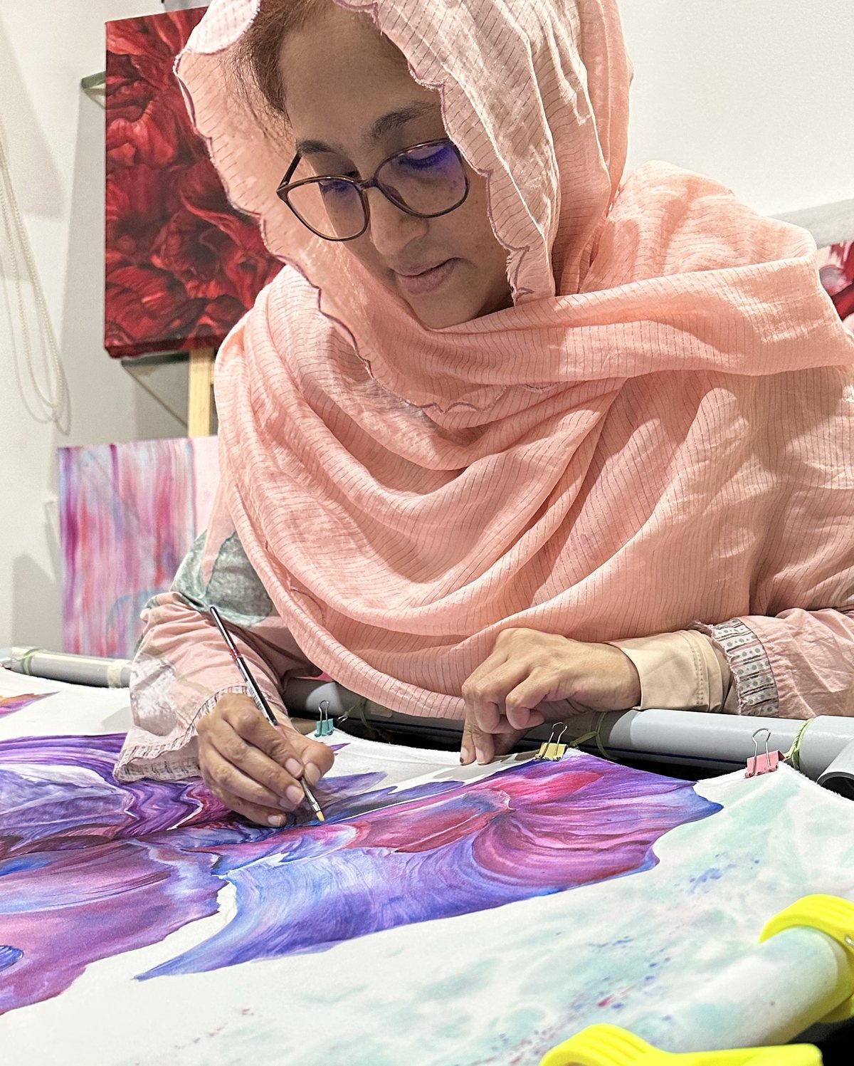 Husna Rafath K. painting a floral design on stretched silk in her studio